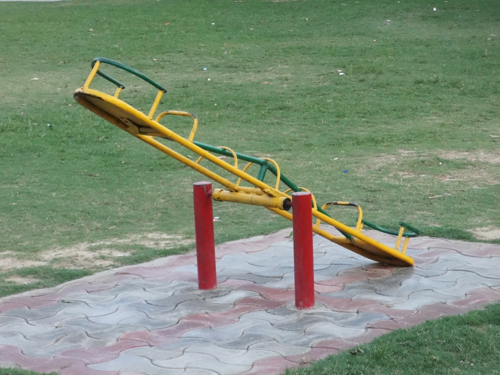 A neglected sea saw in park at early hours in morning, sea saw, park, garden, children, deserted, colorful, green, blue, red